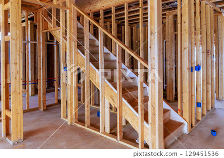 Wooden staircase leading to upper floors being built within framework of new home works area 129451536