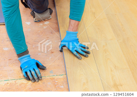 Skilled worker installs new laminate flooring with precision quality craftsmanship. 129451604