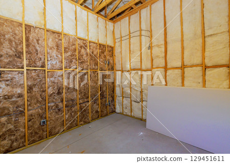 Construction work shows bare room with insulation framed walls, indicating an ongoing renovation project. 129451611