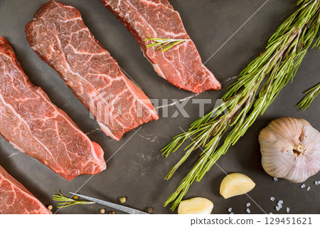 Fresh cuts of beef alongside garlic rosemary ready for delicious grilling session in modern kitchen. Fresh cuts of beef alongside garlic rosemary ready for delicious grilling session in modern kitchen. 129451621