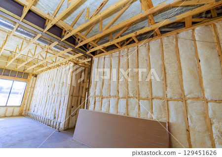 Interior framing, insulation work is underway in residential construction setting during works time hours. Interior framing, insulation work is underway in residential construction setting during works time hours. 129451626