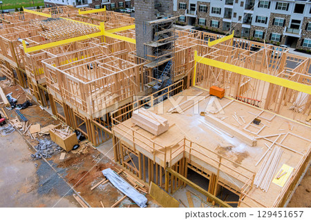 Builders are assembling new housing development featuring wooden beams structures in suburban location under works day 129451657