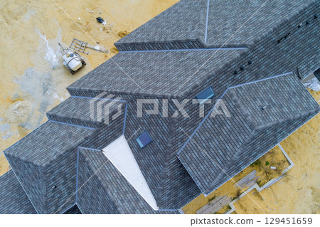 Aerial view of contemporary new roof with unique angles, situated on construction site 129451659