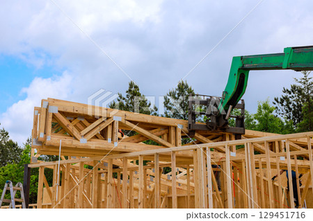 Workers use crane to lift timber truss beams for new structure under works day 129451716