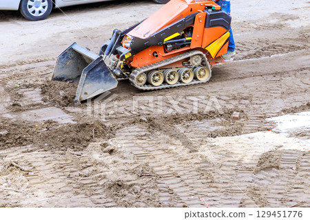 Small construction vehicle is leveling dirt at worksite for construction area Small construction vehicle is leveling dirt at worksite for construction area 129451776