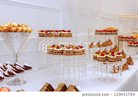 Stunning variety of pastries desserts is elegantly arranged on crystal displays at an upscale event. 129451784