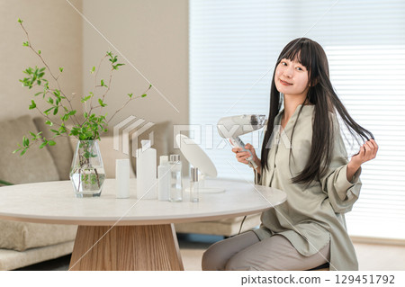 女人用吹風機吹乾頭髮（護髮） 129451792