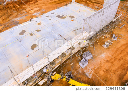 Workers are engaged in building structure, using scaffolding machinery on construction muddy site. Workers are engaged in building structure, using scaffolding machinery on construction muddy site. 129451806