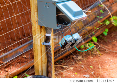 An electrical connection box outlets is installed on wooden post with wires An electrical connection box outlets is installed on wooden post with wires 129451807