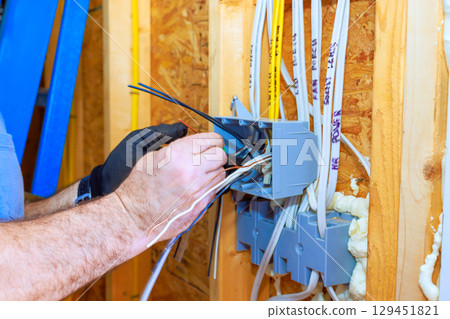 An electrician is installing wiring in newly built home, ensuring safe electrical connections for future use. 129451821