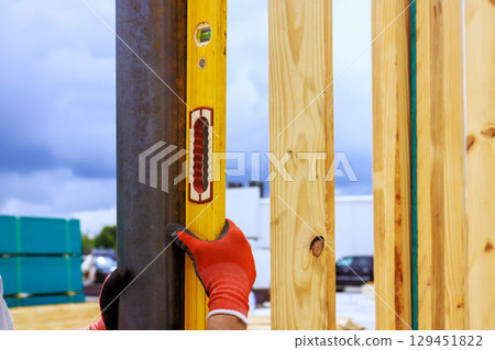 Worker checks alignment of steel column beams using level tool at construction site during work time Worker checks alignment of steel column beams using level tool at construction site during work time 129451822