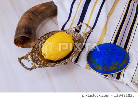 Etrog fruit on silver plate with prayer book kippah to Jewish Sukkot festival holiday traditions. 129451823