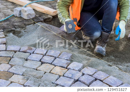 Craftsman arranging cobblestones with precision on construction site in ensuring quality work. 129451827