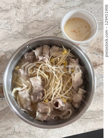 A steaming pot of shabu-shabu with thinly sliced meat, fresh vegetables, and dipping sauces. This Japanese hotpot dish offers a healthy and interactive dining experience. 129451906