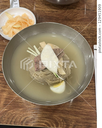 Authentic Pyongyang naengmyeon with chewy buckwheat noodles in cold, clear broth, offering a refreshing and delicate flavor. Perfect for traditional Korean cuisine menus and summer dishes. 129451909