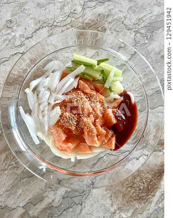 Spicy and tangy bibim guksu with chewy noodles, fresh veggies, and gochujang sauce. A vibrant and refreshing Korean cold noodle dish perfect for a light yet flavorful meal. 129451942