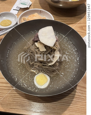 Authentic Pyongyang naengmyeon with chewy buckwheat noodles in cold, clear broth, offering a refreshing and delicate flavor. Perfect for traditional Korean cuisine menus and summer dishes. 129451947