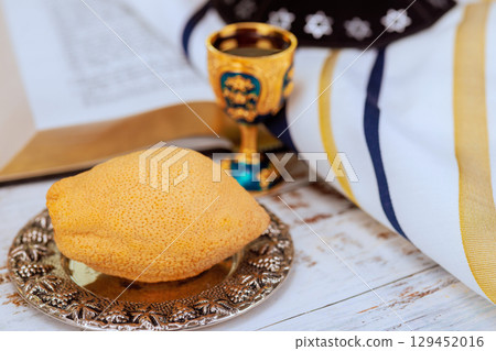Traditional Jewish prayer ritual objects for Sukkot celebration. Etrog fruit on silver plate with kiddush cup to religious ceremony. 129452016