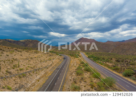 Beeline Highway in Maricopa County, Arizona with two parallel roads cutting through arid Sonoran Desert with its combination of sandy soil, sparse greenery, mountainous horizon. Beeline Highway in Maricopa County, Arizona with two parallel roads cutting through arid Sonoran Desert with its combination of sandy soil, sparse greenery, mountainous horizon. 129452026