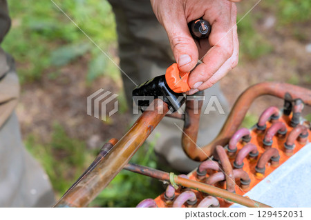 HVAC Contractor hands work on connecting copper tubing with an orange cap under plumbing work HVAC Contractor hands work on connecting copper tubing with an orange cap under plumbing work 129452031