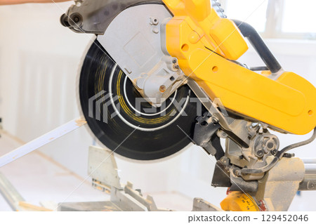 Circular saw is actively cutting wood in well lit construction area, showing precise craftsmanship in progress. Circular saw is actively cutting wood in well lit construction area, showing precise craftsmanship in progress. 129452046