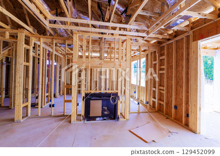 Framed walls of house under construction feature fireplace in center during works day Framed walls of house under construction feature fireplace in center during works day 129452099