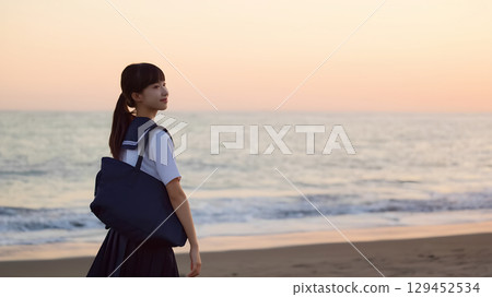 High school girls walking along the beach at sunset 129452534
