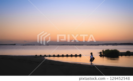 High school girls walking along the beach at sunset 129452548