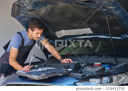 Auto mechanic repairing car engine in garage 129452792