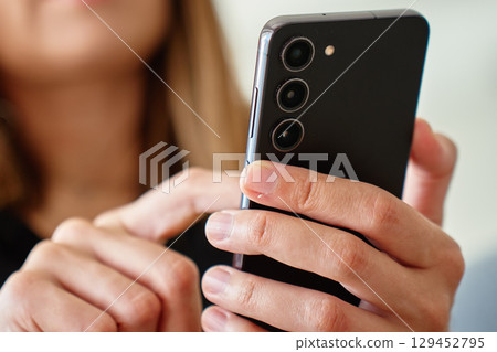 Close up of woman holding smartphone in hand outdoors 129452795