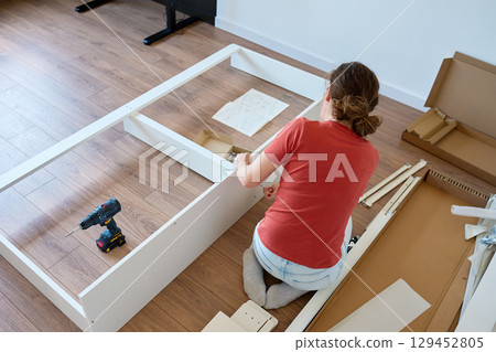Woman assembling furniture at home Woman assembling furniture at home 129452805