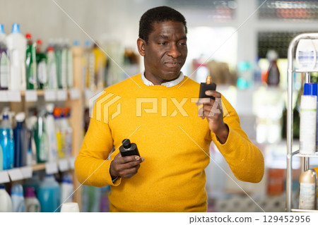 Man shopper choosing scented cosmetics and eau de toilette in supermarket Man shopper choosing scented cosmetics and eau de toilette in supermarket 129452956