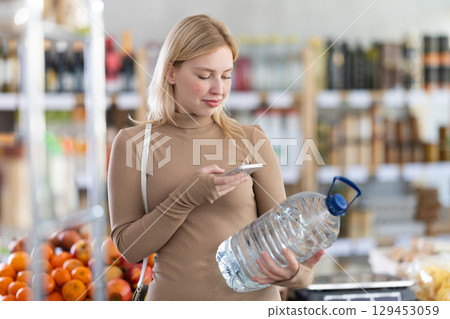 Young woman scanning qr code of water 129453059