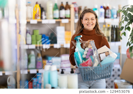 Young woman with full basket choosing something in supermarket Young woman with full basket choosing something in supermarket 129453076