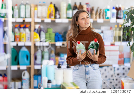 Young woman chooses dishwashing detergent in store 129453077