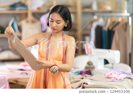 Portrait of positive girl tailor in sewing workshop Portrait of positive girl tailor in sewing workshop 129453100