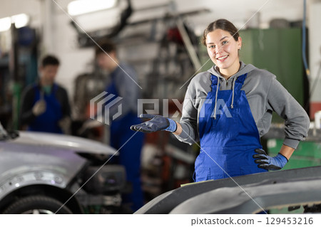 Service station young woman employee works in repair box, department 129453216