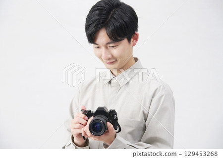 Man holding a film camera on white background 129453268