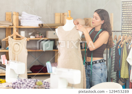 Fashion designer fitting dress on mannequin in dressmaker studio Fashion designer fitting dress on mannequin in dressmaker studio 129453289