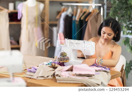Seamstress working on modern sewing machine in sewing workshop 129453294