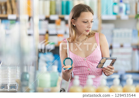 Female shopper in summer clothes chooses best cosmetic in supermarket Female shopper in summer clothes chooses best cosmetic in supermarket 129453544