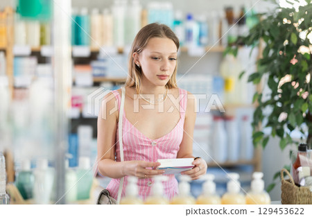 Young woman chooses pills at pharmacy Young woman chooses pills at pharmacy 129453622