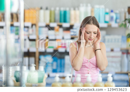 Girl in summer clothes suffers from headache, while visiting household goods supermarket Girl in summer clothes suffers from headache, while visiting household goods supermarket 129453623