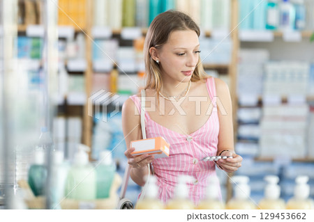 Girl in summer clothes looking for medicine in pharmacy 129453662