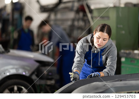 Young woman auto mechanic handle polishes body parts Young woman auto mechanic handle polishes body parts 129453703