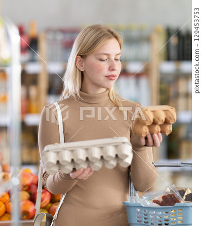 Young woman choosing eggs in grocery store Young woman choosing eggs in grocery store 129453753