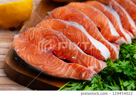 Uncooked salmon steakes on chopping board 129454022