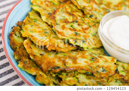 Fritters of courgettes with sour cream 129454123