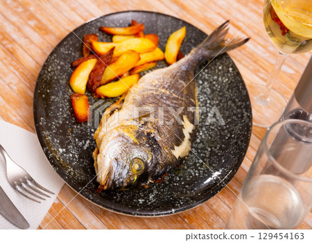Baked dorado with potatoes on plate 129454163