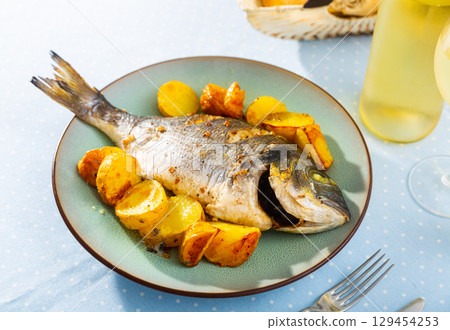 Roasted dorada served on plate with baked potatoes Roasted dorada served on plate with baked potatoes 129454253